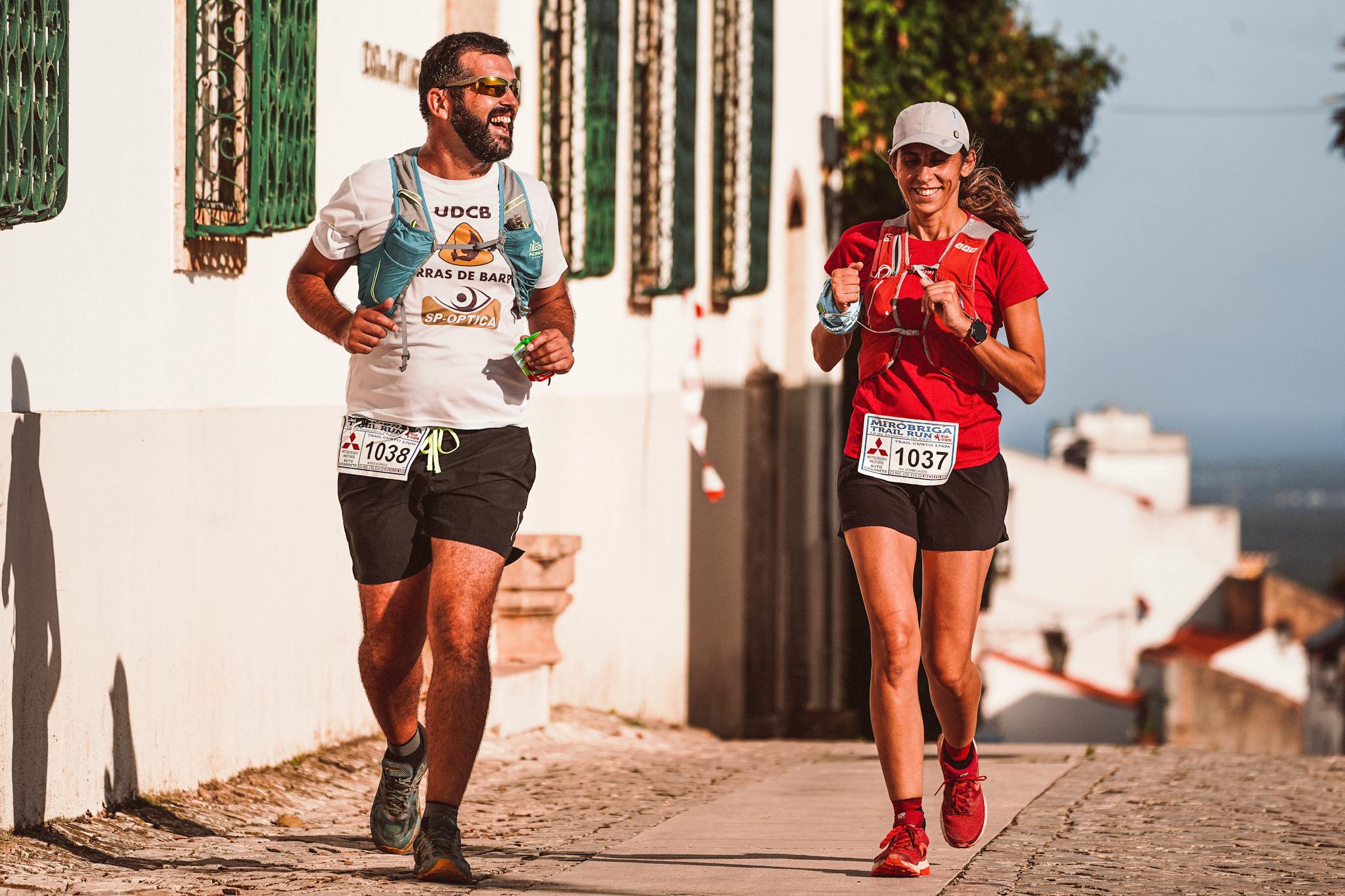 Two runners smiling and enjoying a scenic marathon race, embodying fitness and joy.